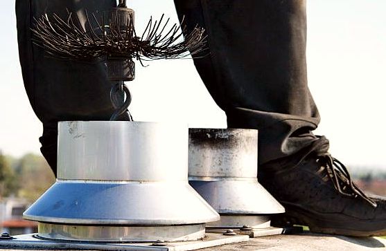 Whip brush resting above two stainless flue collars